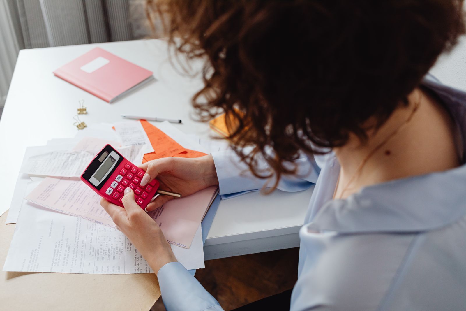 Une personne calcule des dépenses avec une calculatrice et des documents.