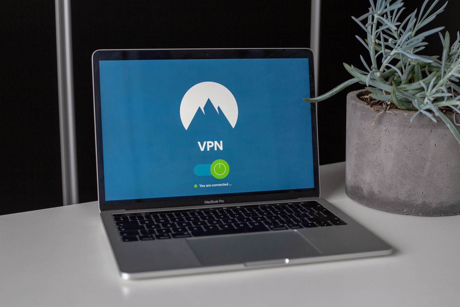 Un ordinateur portable affiche un écran de sécurité (VPN connecté) sur un bureau épuré.