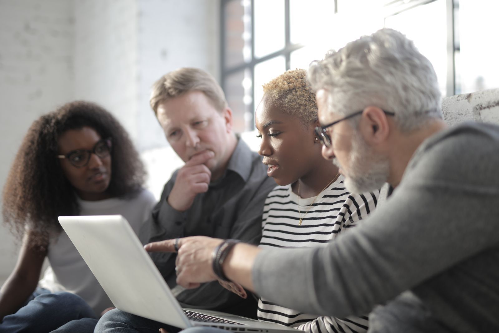 Small team choosing a digital tool around a laptop.